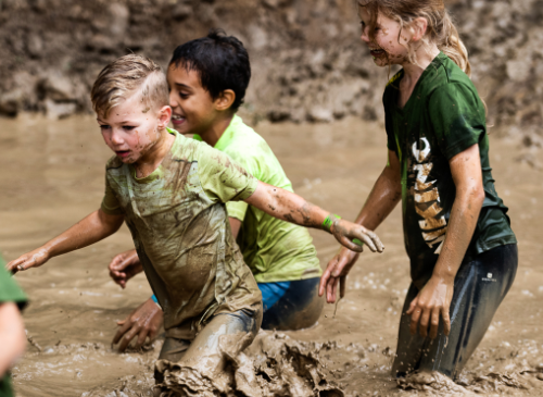 Kinderen die door de modder rennen tijdens een actief obstacle run kinderfeestje nijmegen wijchen amsterdam arnhem gent idee kinderfeestje